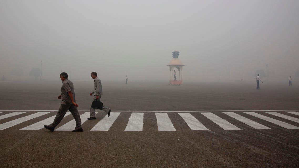 Indians walk to work as Delhi traffic police officers manage an intersection enveloped by smoke and smog, on the morning following Diwali festival in New Delhi, India, Monday, Oct. 31, 2016. AP