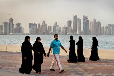 High-rise buildings of downtown Doha, photographed in the background, as women and a man walk by the sea in Doha, Qatar. (File photo: AP)