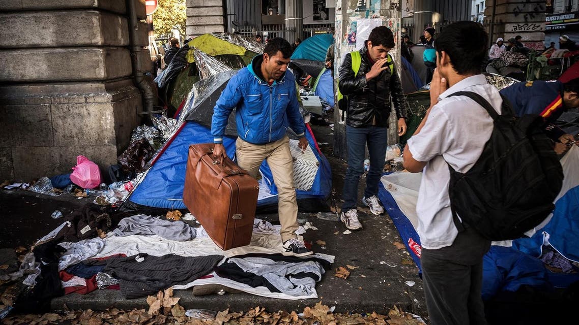 Migrants carry their belongings at a makeshift camp at the Boulevard de la Villette, near the Jaures and Stalingrad metro stations, in northern Paris on October 31, 2016,