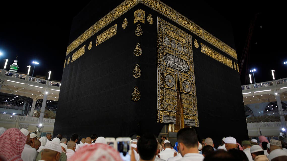 A Saudi policeman (R) stands watch as muslims touch and pray at the door of the Kaaba and touch and kiss the al-Hajr al-Aswad "Black Stone" during their Umrah Mawlid al-Nabawi "Birthday of Prophet Mohammad" in the holy city of Mecca, Saudi Arabia January 18, 2016. Picture taken January 18, 2016. REUTERS
