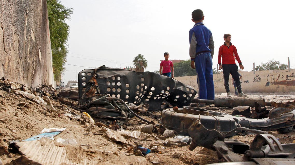 Iraqi youth gather by wreckage at the site of a car bomb that exploded the previous night in Baghdad's Hurriyah neighbourhood on October 31, 2016. AFP