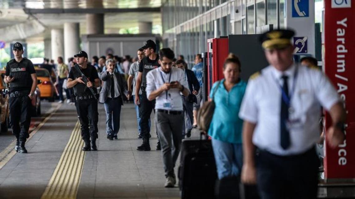Turkish anti riot police officers stand guard as people walk nearby the explosion site at the Ataturk airport International terminal on July 1, 2016 AFP