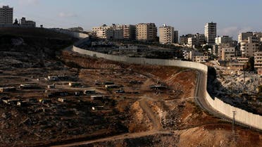 A picture taken on October 18, 2016 from the east Jerusalem Arab neighbourhood of Issawiya shows a view of the Palestinian Shuafat refugee camp (R) behind the controversial Israeli separation wall.  AHMAD GHARABLI / AFP