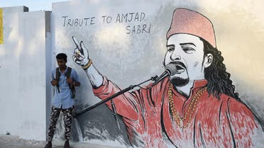 A Pakistani student takes a photograph of his friend next to a wall image of late Sufi musician Amjad Sabri in Karachi on June 27, 2016. One of Pakistan's best known Sufi musicians Amjad Sabri was shot dead by unknown assailants riding a motorcycle in Karachi on June 22, triggering an outpouring of grief over what police described as an "act of terror". ASIF HASSAN / AFP