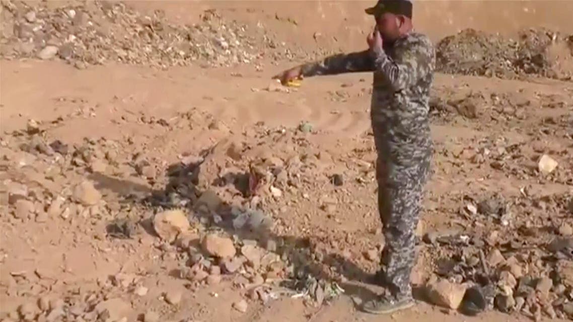 In this Monday, Nov. 7, 2016 frame grab from video, an Iraqi federal police officer holds his nose as he points towards a mass grave in Hamam al-Alil, Iraq. (AP)