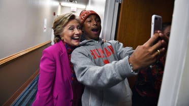 US Democratic presidential nominee Hillary Clinton poses with singer Pharrell Williams for a selfie backstage before a campaign rally in Raleigh, North Carolina, on November 3, 2016. (AFP)