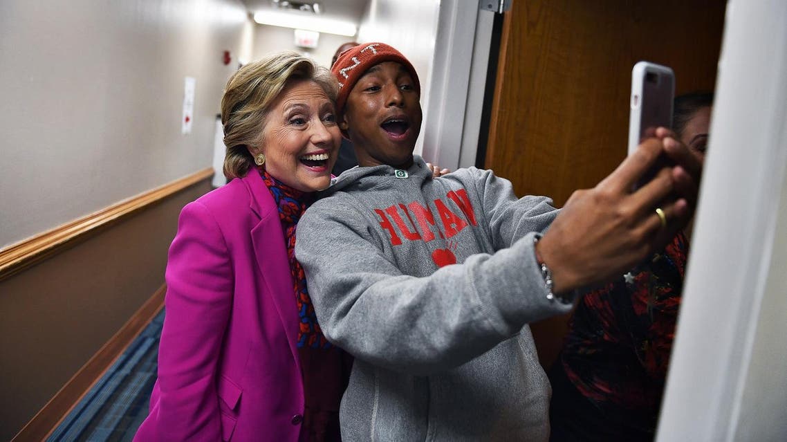 US Democratic presidential nominee Hillary Clinton poses with singer Pharrell Williams for a selfie backstage before a campaign rally in Raleigh, North Carolina, on November 3, 2016. (AFP)