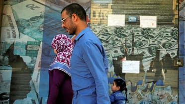 People walk past a closed exchange bureau with an advertisement showing images of the US dollar and other foreign currency in Cairo. (Reuters)