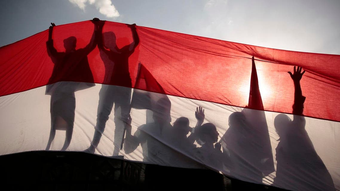 Men are silhouetted against a large representation of the Yemeni flag as they attend a ceremony to mark the anniversary of North Yemen's Sept. 26, 1962 revolution. (AP_