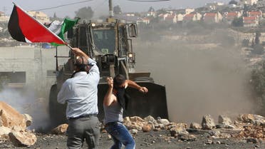 A Palestinian boy throws stones at an armored wheel loader of the Israeli Defense Forces (IDF) during clashes following a protest against the near-by Jewish settlement of Qadomem, in the West Bank village of Kofr Qadom near Nablus October 17, 2014. reuters