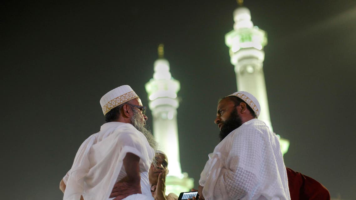 Indian Muslim pilgrims chat in front of the minarets of the Grand Mosque in the holy city of Mecca, Saudi Arabia, late Tuesday, Oct. 8, 2013. The Muslim annual Hajj, or pilgrimage, that will begin on Oct. 14 this year, draws three million visitors each year, making it the largest yearly gathering of people in the world. (AP 