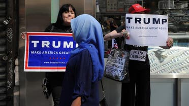 A woman wearing a Muslim headscarf walks past people holding Donald Trump signs before the annual Muslim Day Parade in the Manhattan. (Reuters)