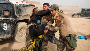 Frontline medics help carry an Iraqi soldier hit by sniper fire in his pelvis area out of their vehicle at an Iraqi Special Forces 2nd division outdoor field clinic in the Samah neighbourhood of Mosul on November 15, 2016.  Odd ANDERSEN / AFP