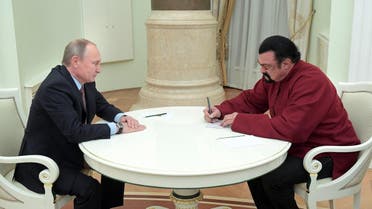 Steven Seagal (R) signs a Russian passport received from Russia's President Vladimir Putin during a meeting at the Kremlin in Moscow. (Reuters)