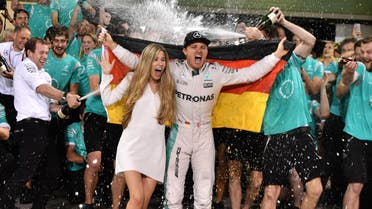 Staff members of Mercedes AMG Petronas F1 Team spray German driver Nico Rosberg (C-R) and his wife Vivian Sibold with champagne as they celebrate at the end of the Abu Dhabi Formula One Grand Prix at the Yas Marina circuit on November 27, 2016. Nico Rosberg won his maiden Formula One world title by securing second place behind his Mercedes arch-rival Lewis Hamilton in the Abu Dhabi Grand Prix. Andrej ISAKOVIC / AFP
