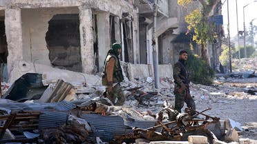 Syrian pro-government forces walk past destroyed buildings in the Baadeen district in eastern Aleppo on November 28, 2016, a day after they took control of the area from rebel fighters as part of their assault to retake the entire northern city. Government forces have retaken a third of rebel-held territory in Aleppo, forcing nearly 10,000 civilians to flee as they pressed their offensive to retake Syria's second city. In a major breakthrough in the push to retake the whole city, regime forces captured six rebel-held districts of eastern Aleppo over the weekend, including Masaken Hanano, the biggest of those in eastern Aleppo.  GEORGE OURFALIAN / AFP