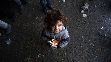 A Syrian child, who fled with his family from rebel-held areas in the city of Aleppo, reacts as he holds a sandwich. (AFP)