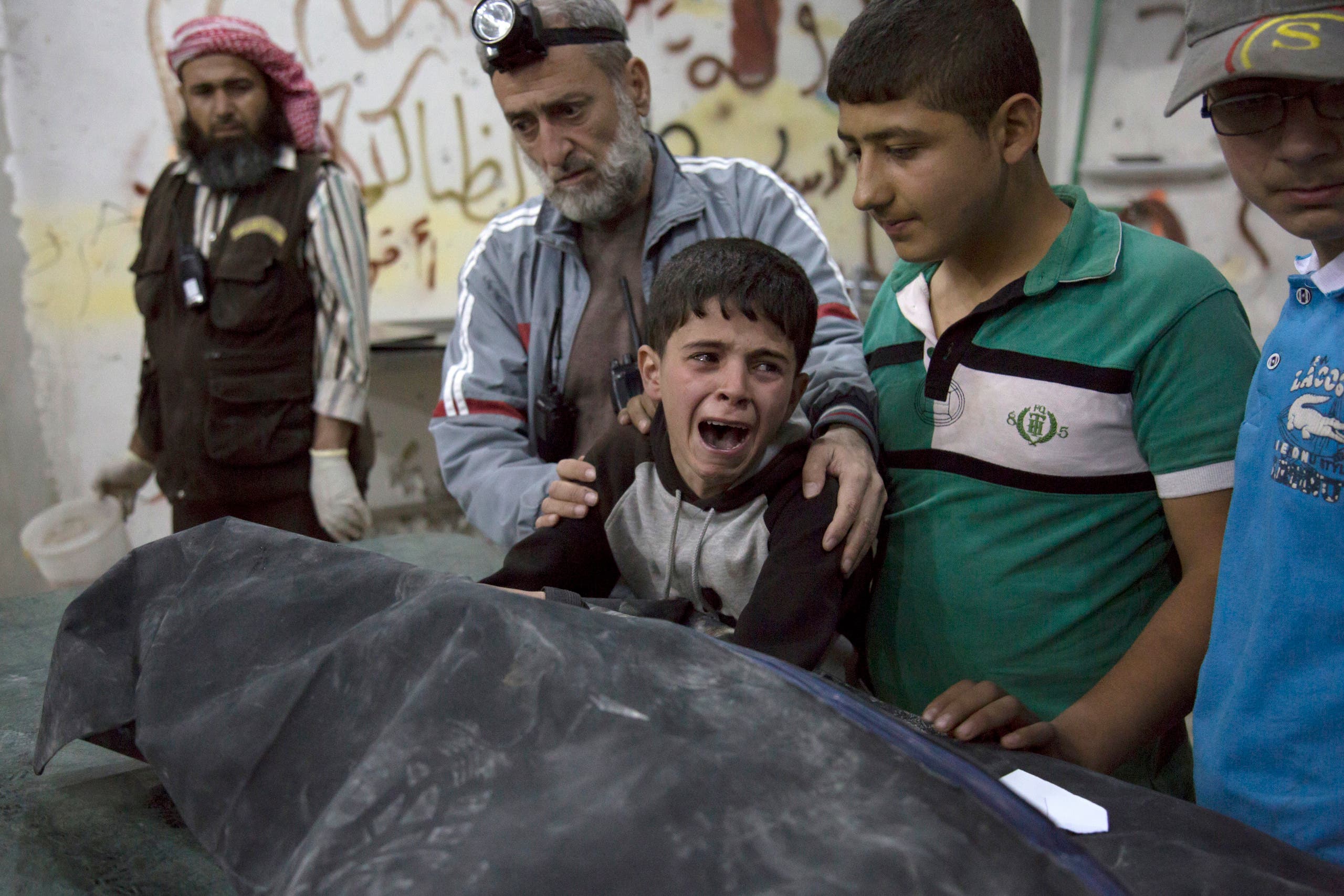 A Syrian boy is comforted as he cries next to the body of a relative who died in a reported airstrike on April 27, 2016 in the rebel-held neighbourhood of al-Soukour in the northern city of Aleppo. KARAM AL-MASRI / AFP