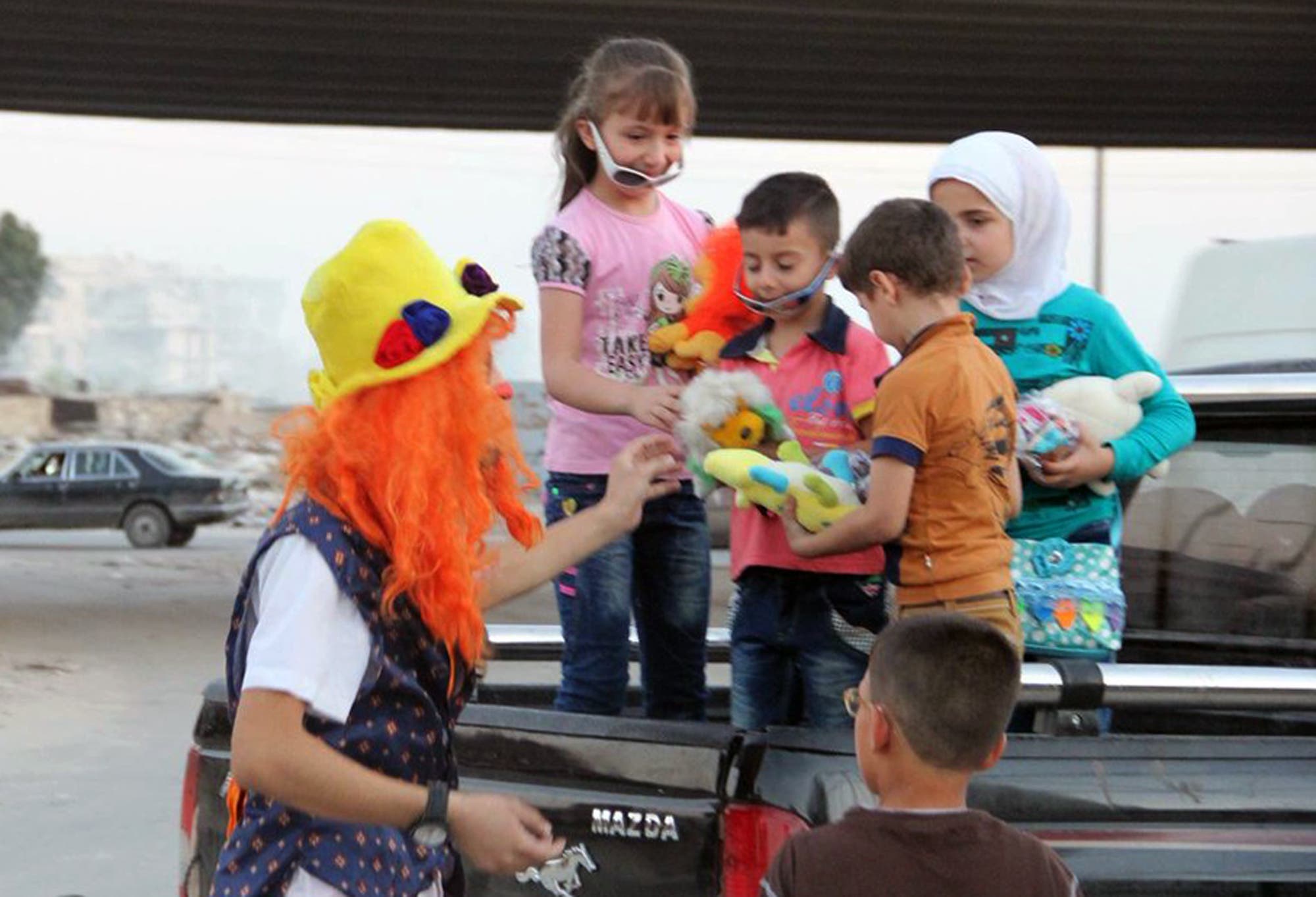 This undated photo courtesy of Ahmad al-Khatib, a media activist in Aleppo, shows Syrian social worker Anas al-Basha, 24, dressed as a clown, distributing toys to children in Aleppo, Syria. AP