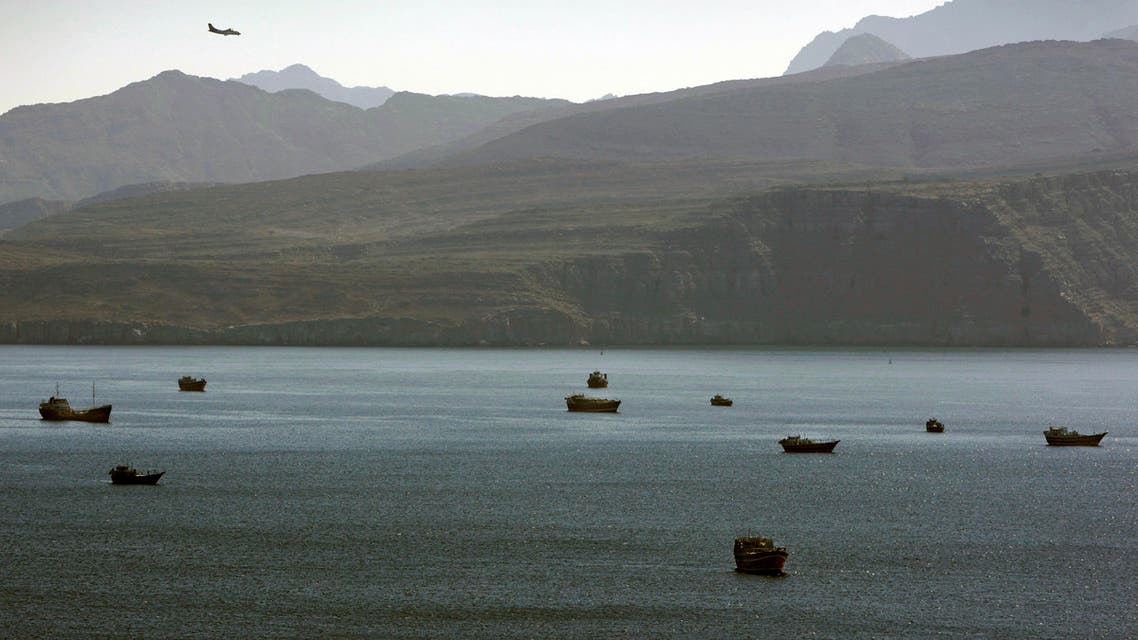 In this Jan. 19, 2012 photo, a plane flies over the mountains in south of the Strait of Hormuz as the trading dhows and ships are docked on the Persian Gulf waters near the town of Khasab, in Oman. ap