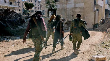 Rebel fighters walk down a street west of the northern Syrian city of Aleppo on December 9, 2016