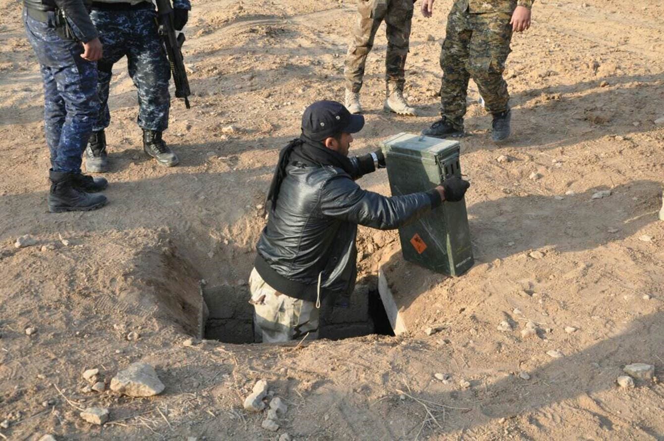 جندي عراقي يقوم بإخراج صناديق أسلحة لداعش وضعت في نفق تحت الأرض في الموصل