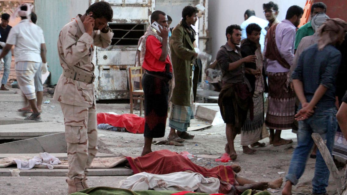 Yemenis gather around bodies lying covered on the ground on December 10, 2016 after a suicide bomber killed 35 soldiers and wounded around 50 others at a military camp in Yemen's southern city of Aden. afp