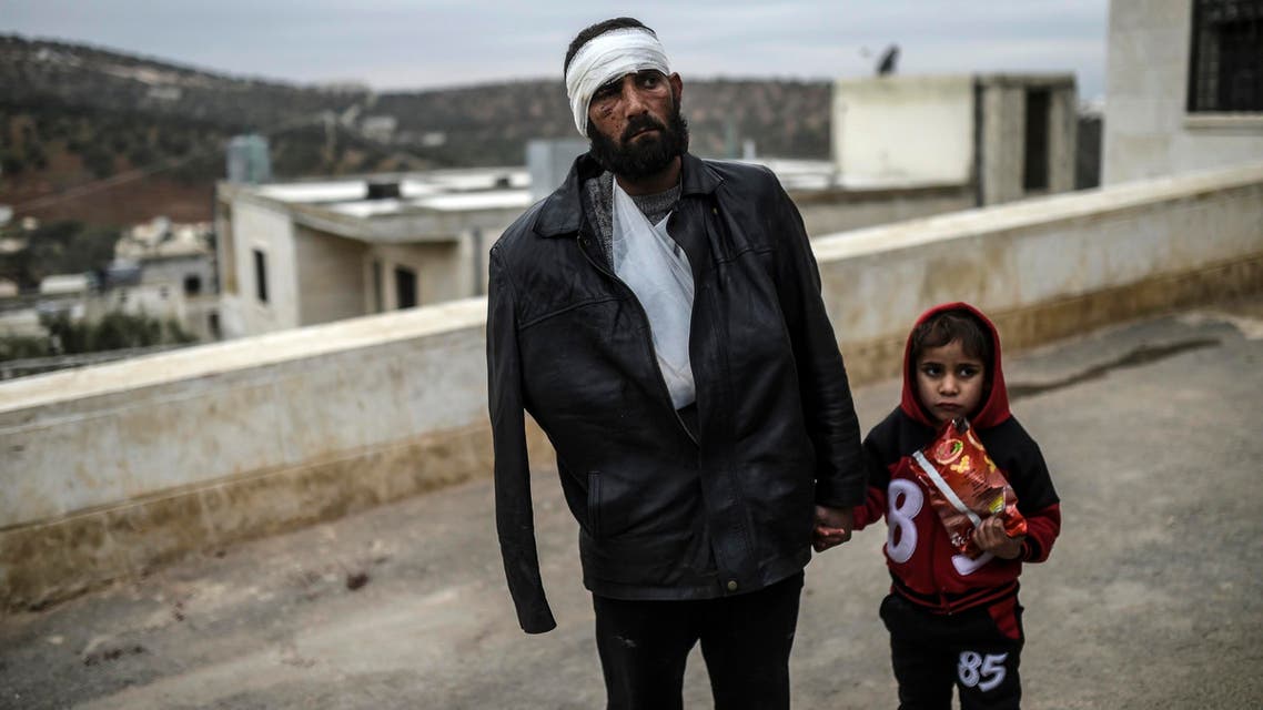 An injured Syrian man who just arrived on the Syrian side of the Bab al-Hawa border crossing between Syria and Turkey waits with his child outside a hospital on December 16, 2016. The Syrian government suspended the evacuation of the last rebel-held parts of Aleppo, but a military source denied a Russian statement that the operation was "complete." (AFP)