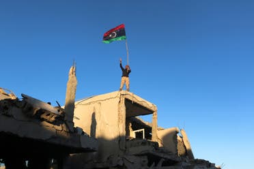 A fighter of Libyan forces allied with the UN-backed government waving a Libyan flag flashes victory sign as he stands atop the ruins of a house after forces finished clearing Ghiza Bahriya, the final district of the former ISIS stronghold of Sirte, Libya. (Reuters)