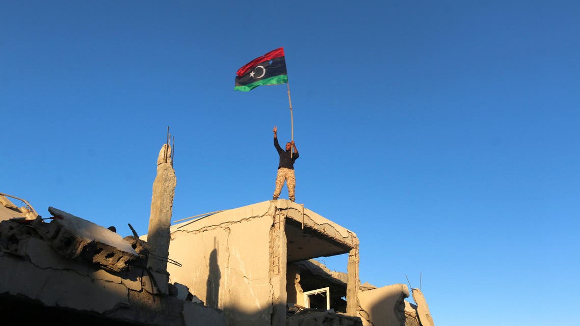 A fighter of Libyan forces allied with the UN-backed government waving a Libyan flag flashes victory sign as he stands atop the ruins of a house after forces finished clearing Ghiza Bahriya, the final district of the former ISIS stronghold of Sirte, Libya. (Reuters)