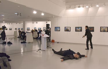 This picture taken on December 19, 2016 shows Andrey Karlov (2ndR), the Russian ambassador to Ankara, lying on the floor after being shot by a gunman (R) during an attack during a public event in Ankara. AFP