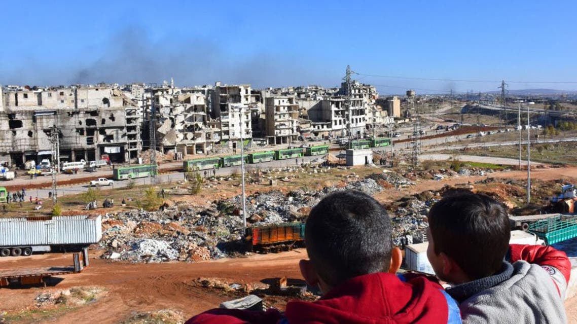 أطفال سوريون من حلب يشاهدون مغادرة الحافلات الخضراء التي تنقل المسلحين وأفراد أسرهم، 15 ديسمبر 2016