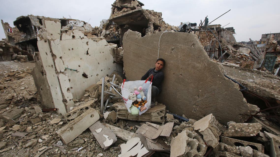 A Syrian boy sits with belongings he collected from the rubble of his house in Aleppo's Al-Arkoub neighbourhood on December 17, 2016, after pro-government forces retook the area from rebel fighters. Youssef KARWASHAN / AFP