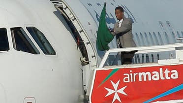 One of the hijackers of a Libyan Afriqiyah Airways Airbus A320 waves a Gaddafi-era Libyan flag at Malta Airport, December 23, 2016. (Reuters)