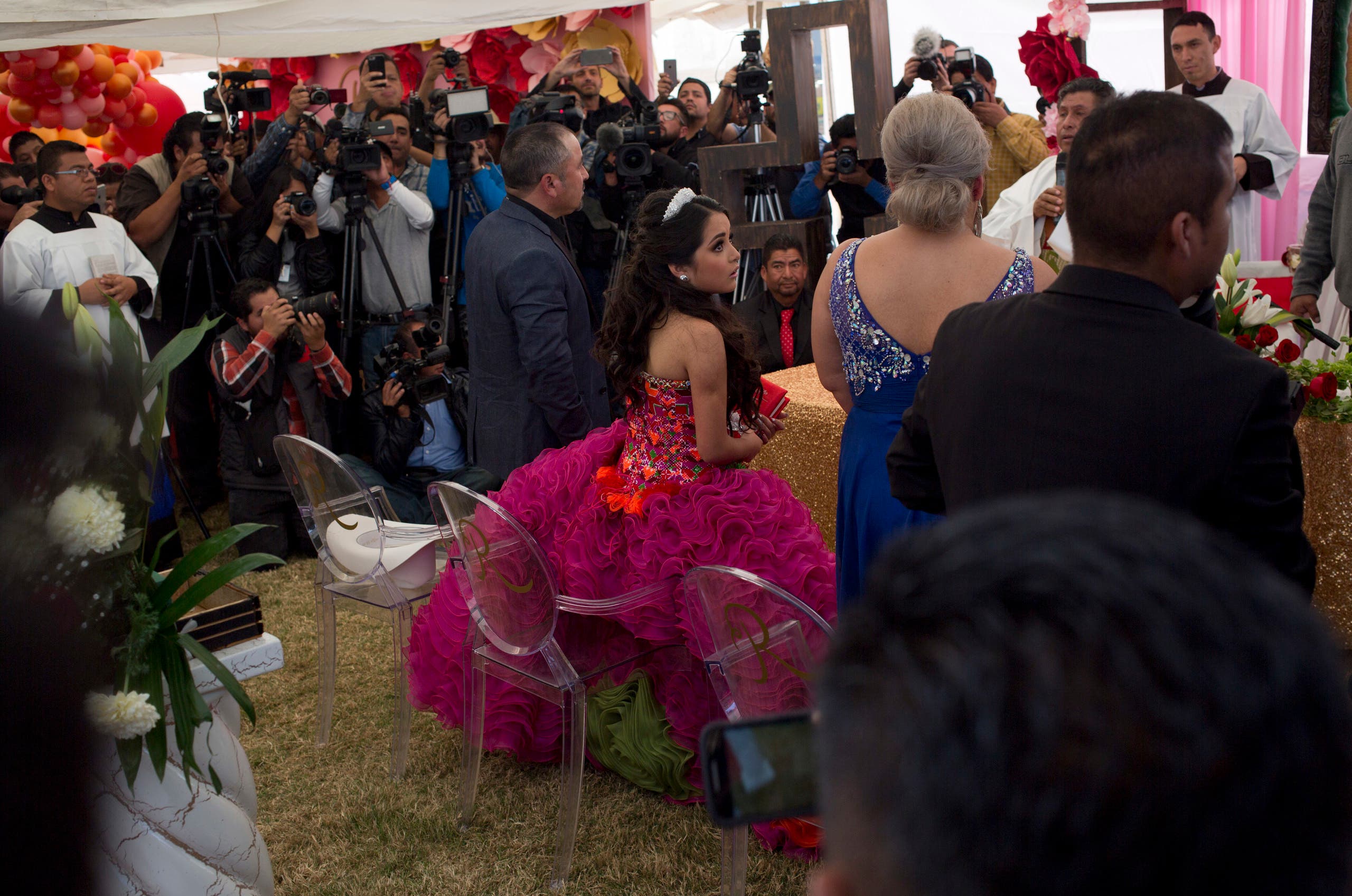 Rubi Ibarra looks at her mother Anaelda as journalists struggle to get images during a Mass as part of Rubi's down-home 15th birthday party in the village of La Joya, San Luis Potosi State, Mexico, Monday, Dec. 26, 2016. AP