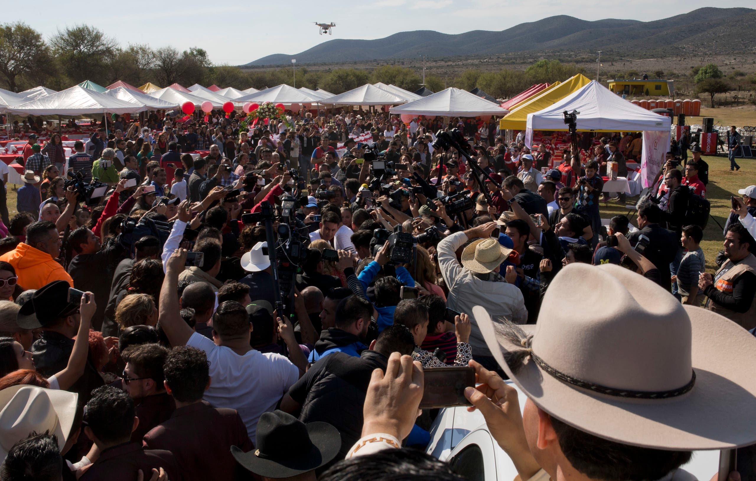 Rubi Ibarra, not seen, arrives at the site of a Mass that is part of her down-home 15th birthday party, surrounded by a horde of journalists and a drone flying overhead, in the village of La Joya, San Luis Potosi State, Mexico, Monday, Dec. 26, 2016. AP