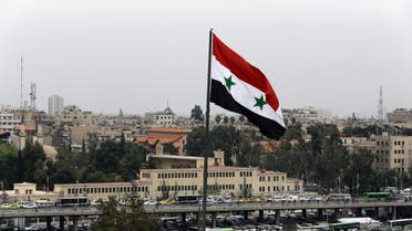 A Syrian flag flies near a bus station in the Baramkeh neighbourhood of the capital Damascus on November 5, 2015. The President Bridge can be seen in the background. AFP PHOTO / LOUAI BESHARA 