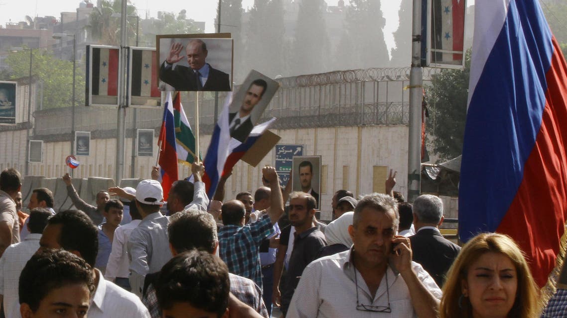 Several hundred people, holding up Russian and Syrian flags as well as portraits of the two countries' presidents, gather near the Russian embassy in Damascus on October 13, 2015 to express their support for Moscow's air war in Syria, just before two rockets struck the embassy compound sparking panic among the crowd. AFP PHOTO/LOUAI BESHARA