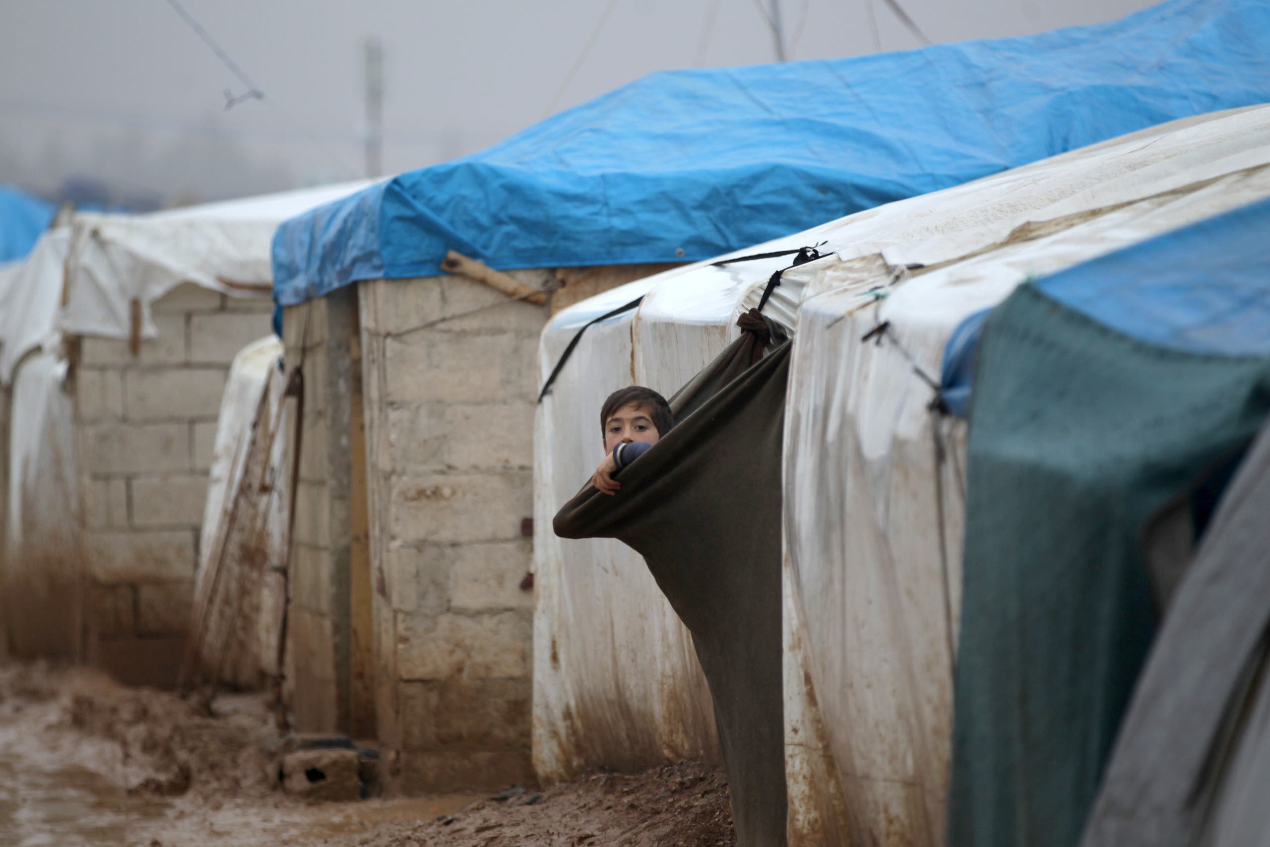 An internally displaced Syrian boy looks out his tent in the Bab Al-Salam refugee camp, near the Syrian-Turkish border, northern Aleppo province, Syria December 26, 2016. REUTERS/Khalil Ashawi