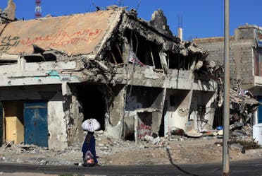 A Libyan woman walks past the rubble of a building in the Mediterranean city of Sirte. (AFP)