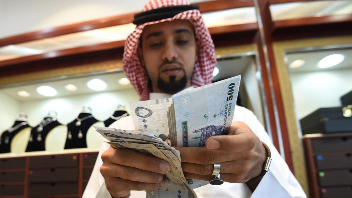 A Saudi man counts banknotes at his jewelry shop at Tiba market in Riyadh, on October 3, 2016. Since 2014 global oil prices have collapsed by more than half, leaving Saudi Arabia with a record deficit last year. The shortfall in the kingdom's main revenue source had already led to unprecedented subsidy cuts and a slowdown in government projects as the administration tries to diversify the economy. FAYEZ NURELDINE / AFP