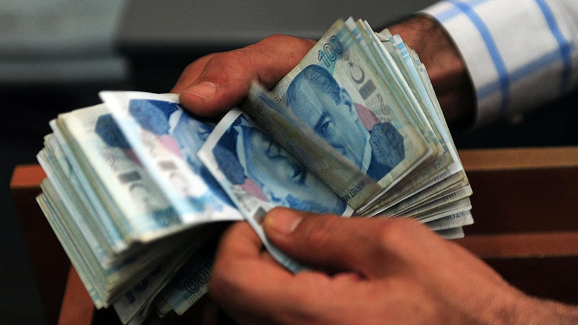 An exchange office worker counts Turkish lira banknotes in Istanbul on June 8, 2015. Turkish shares fell over 6 percent in morning trade and the lira plunged to a new record low against the dollar, as investors took fright at new political uncertainty following legislative elections. AFP PHOTO / OZAN KOSE