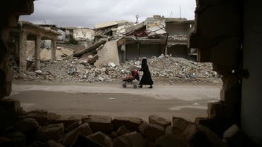 A woman pushes a baby trolley past damaged buildings in the rebel held besieged city of Douma, in the eastern Damascus suburb of Ghouta, Syria January 8, 2017. REUTERS/Bassam Khabieh TPX IMAGES OF THE DAY