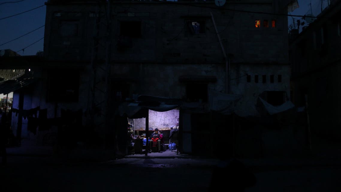 A Palestinian man sits as he sells vegetables in a makeshift shop lit with a lamp powered by a battery during a power cut in Beit Lahiya in the northern Gaza Strip January 11, 2017. Picture taken January 11, 2017. REUTERS/