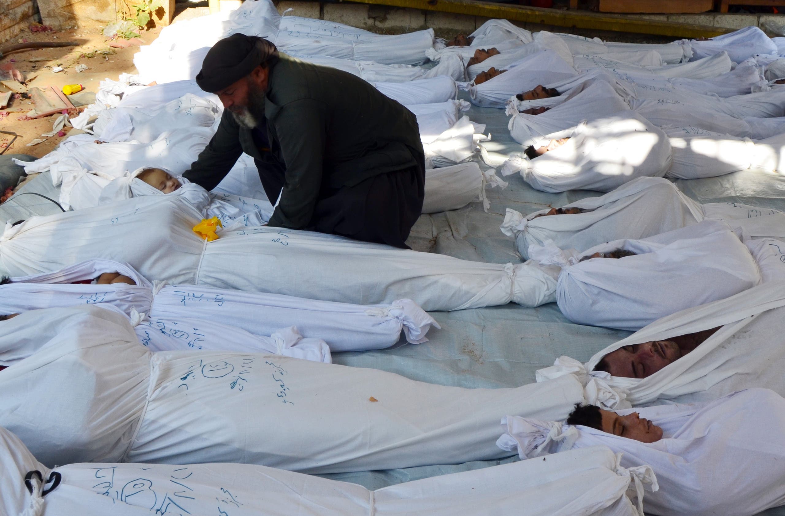 A man holds the body of a dead child among bodies of people activists say were killed by nerve gas in Ghouta, a rebel-controlled suburb of the Syrian capital Damascus, Syria August 21, 2013. REUTERS
