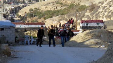 People are seen crossing at an army checkpoint, as rebel fighters and their families prepare to leave the town of Deir Kanun in the Wadi Barada region, on January 11, 2017,