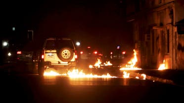 Molotov cocktails thrown by anti-government protesters, unseen, who ran out from narrow side streets to strike a passing police convoy, burn on the road in this image taken through a car windshield in Daih village. (File photo: AP)