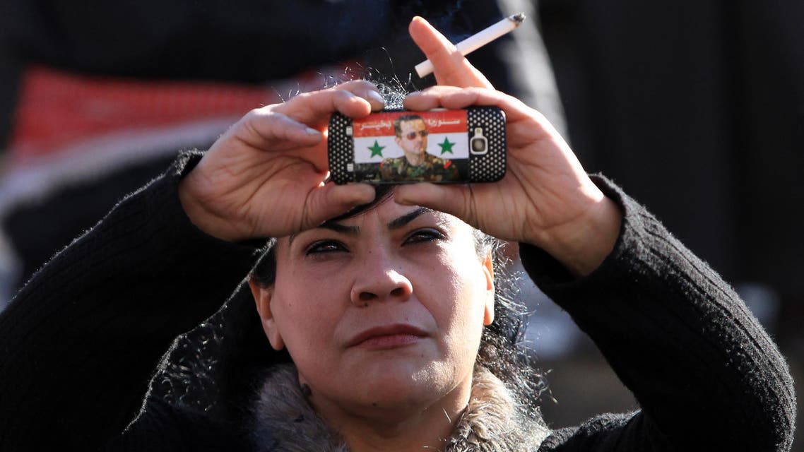 Syrian government supporter takes pictures with her mobile phone bearing a sticker of Syrian President Bashar al-Assad during a pro-regime rally in Damascus on January 27, 2012. AFP