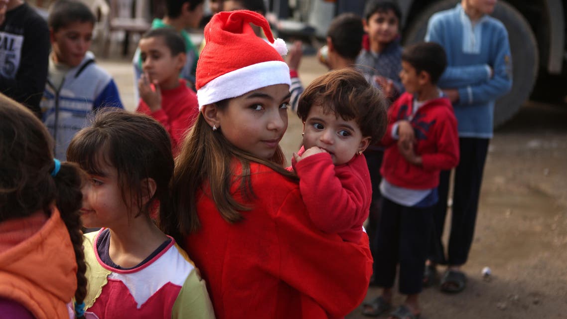 Chloe, a Lebanese Christian teenager dressed as Santa Claus, holds a Syrian refugee on December 24, 2016 during a gift distribution organised by the maronite congregation "Mission de Vie" in a slum in the town of Dbayeh, north of Beirut. (AFP)