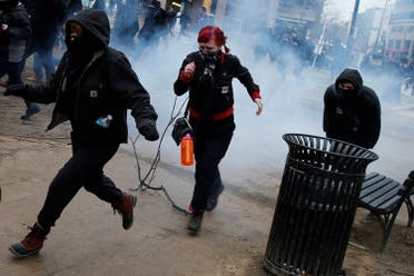 Activists run after being hit by a stun grenade while protesting against Trump on the sidelines of the inauguration in Washington. (Reuters)